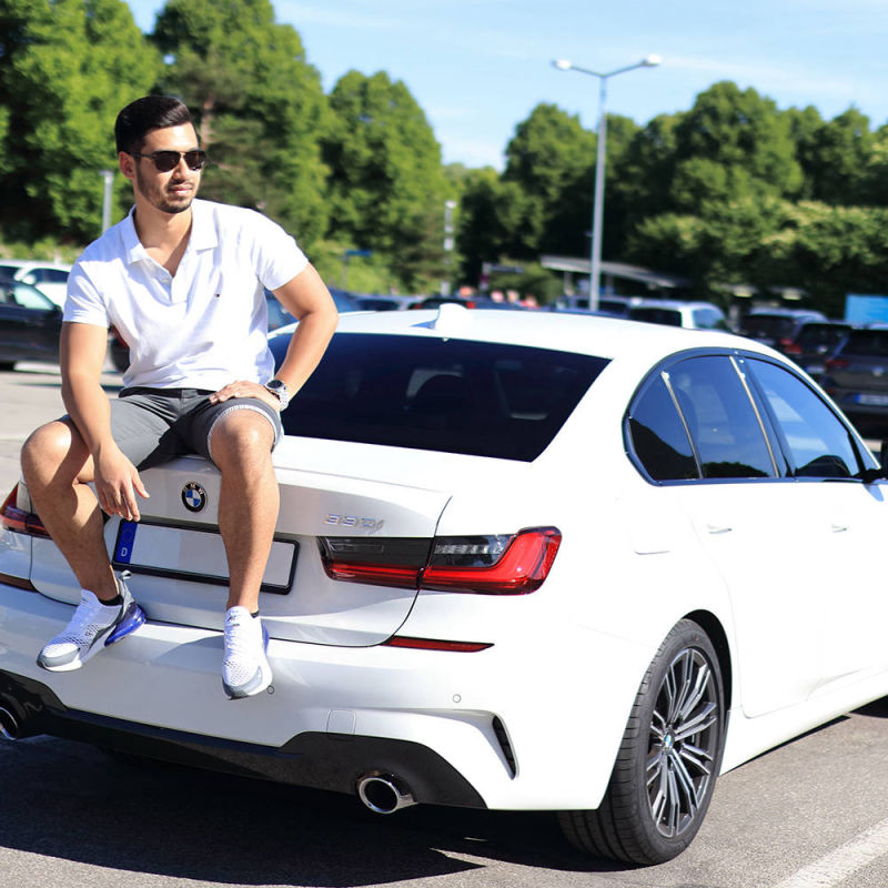 Junger Mann sitzt auf einer weißen 330 M Paket 3er BMW Limousine