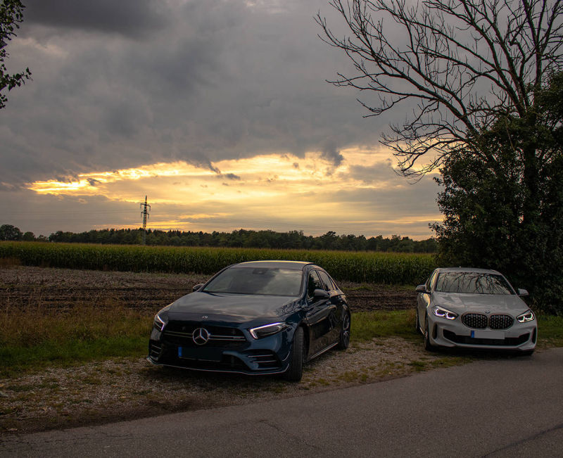 Zwei Sportwagen beim Sonnenuntergang, A35 AMG Mercedes Benz Limousine und BMW 135 M Paket in weiß